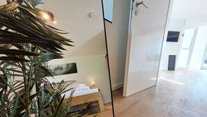 Hotelkamer met een bed, nachtkastje, lamp, schilderij aan de muur en een grote spiegel.