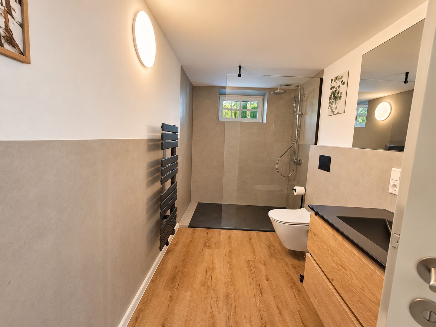 A modern bathroom with a shower, toilet, and a wooden floor.