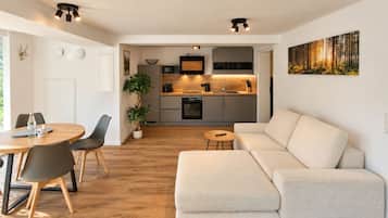 Ein modernes Wohnzimmer mit einer Couch, einem Couchtisch und einem Essbereich mit Stühlen und einem Tisch.