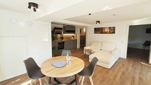 Een moderne woonruimte met een eethoek, een bank en een keuken op de achtergrond.