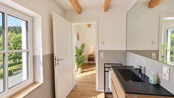 Eine moderne Küche mit einer schwarzen Arbeitsplatte, einem Spülbecken und einem Fenster mit Blick auf einen Garten.