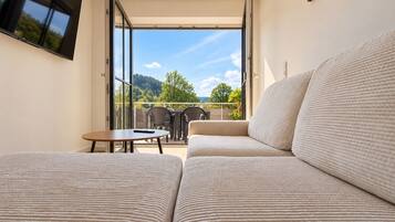 Ein modernes Zimmer mit einer Couch, einem Tisch und einem an der Wand befestigten Fernseher.