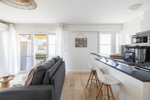 Eine moderne Wohnung mit Küche, einem grauen Sofa und einem Essbereich.