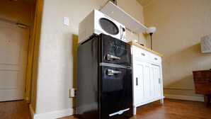 Une cuisine de taille réduite avec un réfrigérateur noir, un four à micro-ondes et un meuble blanc.