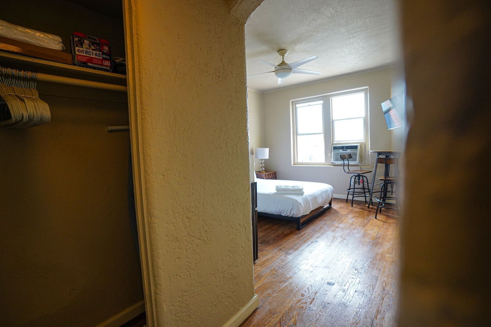 Un dormitorio con cama, ventilador de techo y ventana.