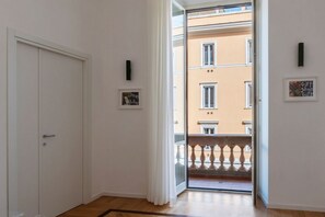 A hallway with a white door, a glass door leading to a balcony, and a framed picture on the wall. - A bright and welcoming 60 square meters apartment, perfect for two people, located on the second floor of a period building with an elevator (NOT accessible to disabled guests).The property is located in the elegant Prati district, close to the Vatican C (Rome)
