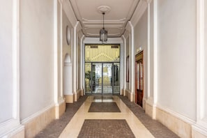 A hallway with a double door, a hanging light fixture, and a patterned floor. - A bright and welcoming 60 square meters apartment, perfect for two people, located on the second floor of a period building with an elevator (NOT accessible to disabled guests).The property is located in the elegant Prati district, close to the Vatican C (Rome)