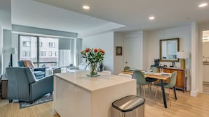 Un apartamento moderno con isla de cocina, comedor y sala de estar con sofá y planta.