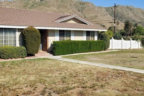 A single-story house with a front porch, a well-maintained lawn, and a white picket fence. - < 1 Mi to UC Riverside! Extended Base for Families (Riverside)