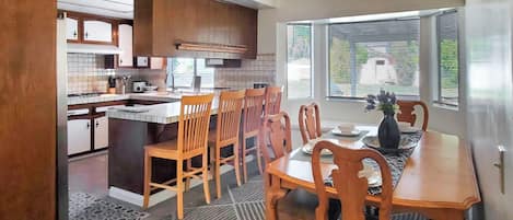 A kitchen with wooden cabinets, a dining table with chairs, and a ceiling fan.