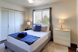 Ein Schlafzimmer mit Bett, Nachttischen, einem Fenster und einem Kleiderschrank.