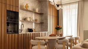 A modern kitchen with built-in appliances, wooden cabinetry, a marble backsplash, and a dining area with a round table and chairs. - Luxury A/C Apt - 10P/4BDR - Arc de Triomphe (Paris)