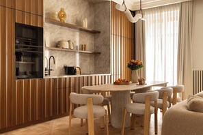 Eine moderne Küche mit integrierten Geräten, Holzschränken, einer Marmor-Spritzschutzwand und einem Essbereich mit rundem Tisch und Stühlen.