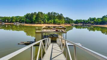 A dock extending into calm water with a clear view of a forested shoreline.