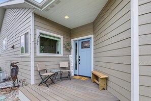 A house with a porch, a blue door, a welcome sign, a bench, and outdoor furniture. - Next to Public Golf Course! Kalispell Townhome (Kalispell)