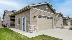 Ein eingeschossiges Haus mit Garage, einer Veranda und einer Wand aus Naturstein.