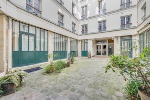 Ein Innenhof mit befestigtem Boden, Blumentöpfen und einem Hauseingang.
