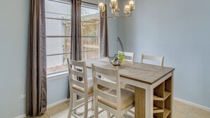 Un espace repas comprenant une table, des chaises et un lustre.