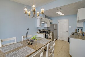 A kitchen with a dining table, chairs, a chandelier, cabinets, a refrigerator, and a microwave. - Private Patio! Family Home in Corpus Christi (Corpus Christi)