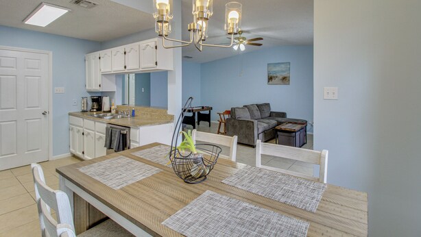 Un espace repas comprenant une table en bois, des chaises, un lustre et un ventilateur de plafond.