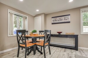 A dining area with a round table, four chairs, a small plant, and a wall-mounted sign. - Walk to Theaters & Dining! Ridgefield Gem w/ Yard (Ridgefield)
