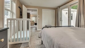 Un dormitorio con una cuna, una cama, un vestidor y un ventanal corredera que da a un balcón.