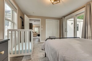 A bedroom with a crib, a bed, a walk-in closet, and a sliding glass door leading to a balcony. - Walk to Theaters & Dining! Ridgefield Gem w/ Yard (Ridgefield)