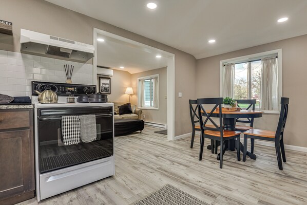 A modern kitchen with a stove, oven, and dining area with chairs and a table. - Walk to Theaters & Dining! Ridgefield Gem w/ Yard (Ridgefield)