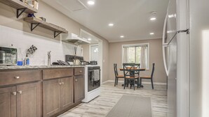 Una cocina con armarios de madera, una estufa y un comedor con mesa y sillas.
