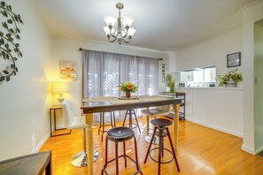 A dining area with a table, bar stools, a chandelier, a potted plant, and a kitchen in the background. - Family Gem w/ Pet-Friendly Yard! 8 Mi to Riverside (Moreno Valley)