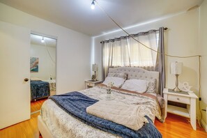 A bedroom with a bed, bedside tables, a mirror, and a window with curtains. - Family Gem w/ Pet-Friendly Yard! 8 Mi to Riverside (Moreno Valley)