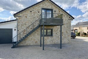 A stone building with a balcony, a staircase, and a garage. - Premium Couples Lodge With Jacuzzi (Malmedy)