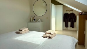 Une chambre à coucher avec deux lits, une commode, un miroir et une armoire.