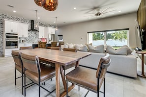 A modern kitchen with white cabinets, a large dining table, and a built-in oven. - Private Yard & Covered Patio: Modern Tampa Getaway (Tampa)