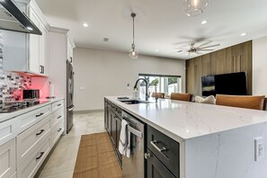 A modern kitchen with white cabinetry, a marble island, a built-in oven, and a ceiling fan. - Private Yard & Covered Patio: Modern Tampa Getaway (Tampa)