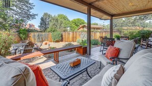 Eine Außenpatio mit überdachter Sitzgruppe, einem Holzzaun und Blick auf eine natürliche Landschaft.