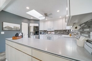 A modern kitchen with a central island, white cabinets, a microwave, and a ceiling fan. - Walk or Bike to Cathedral Rock! Home w/ Views (Sedona)