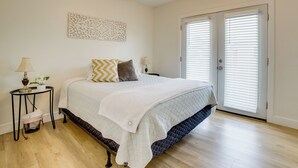 A bedroom with a bed, a nightstand, a lamp, a wall art piece, and a door with blinds. - Family Home 5 Mi to Dtwn Riverside & Hospital! (Riverside)