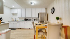 A modern kitchen with white cabinets, a stainless steel refrigerator, and a dining area with a wooden table and chairs. - Family Home 5 Mi to Dtwn Riverside & Hospital! (Riverside)