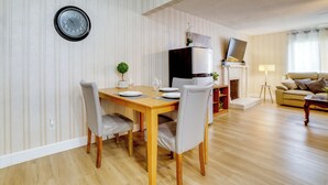 A dining area with a wooden table, chairs, a clock, and a TV on a stand. - Family Home 5 Mi to Dtwn Riverside & Hospital! (Riverside)