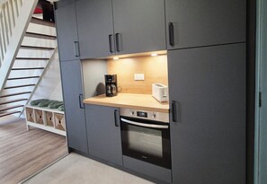 A compact kitchen with a built-in oven, a coffee maker, and a toaster on the countertop. - Renovated duplex apartment in residence on 3rd floor with elevator. (Roscoff)