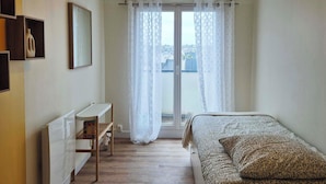 A bedroom with a bed, a desk, a chair, a radiator, and a window with curtains. - Renovated duplex apartment in residence on 3rd floor with elevator. (Roscoff)