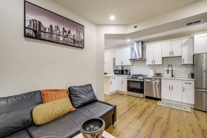 A modern kitchen with white cabinets, stainless steel appliances, and a cityscape painting on the wall. - Renovated NE Washington Home Base w/ Shared Yard! (Washington)