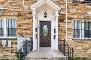 A stone building with a central entrance, a dark wooden door, and a small porch with a metal railing. - Renovated NE Washington Home Base w/ Shared Yard! (Washington)