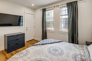 A bedroom with a bed, a dresser, a TV, and a window with curtains. - Renovated NE Washington Home Base w/ Shared Yard! (Washington)