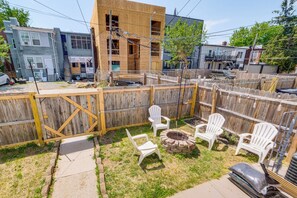 A fenced backyard with white plastic chairs, a fire pit, and a wooden deck. - Renovated NE Washington Home Base w/ Shared Yard! (Washington)