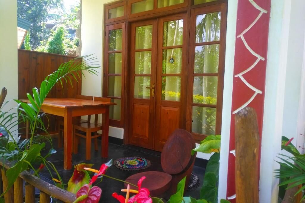 A wooden door with frosted glass panels, a wooden table, a chair, and potted plants.