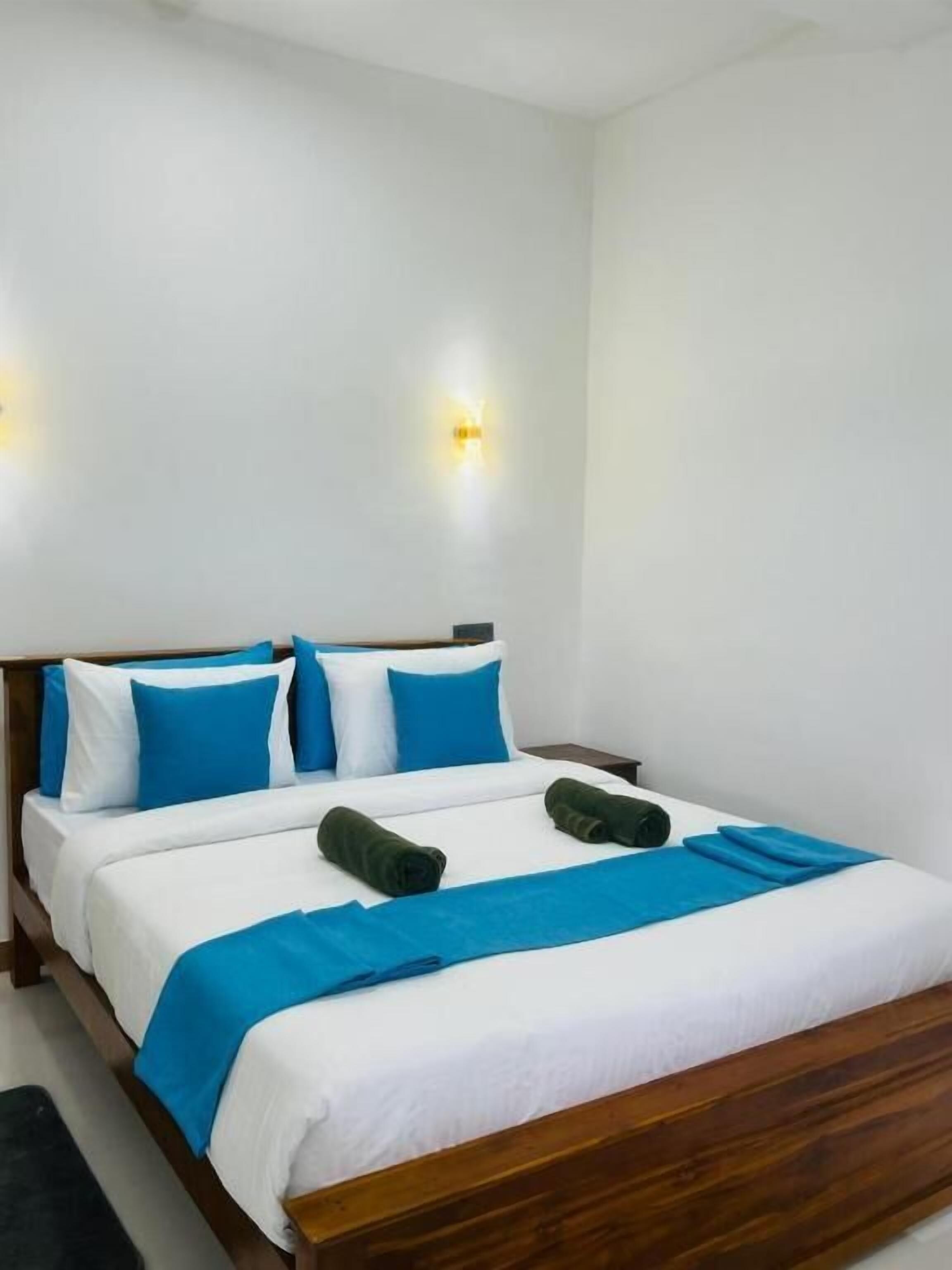Quarto com cama de madeira, roupa de cama branca e detalhes em azul.