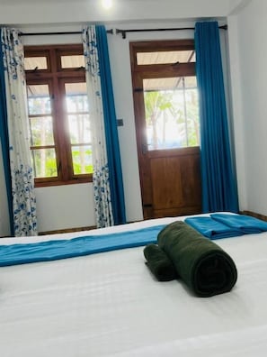 Quarto de hotel com cama, cortinas e janela com vista para o verde.