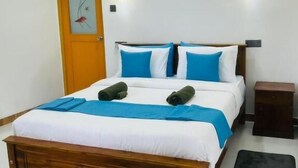 Una cama bien hecha con ropa de cama azul y blanca, un cabecero de madera y dos mesitas de noche.